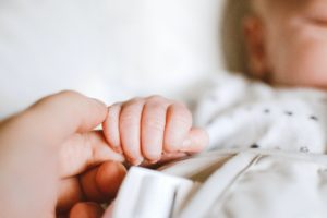 Person holding sleeping baby's hand